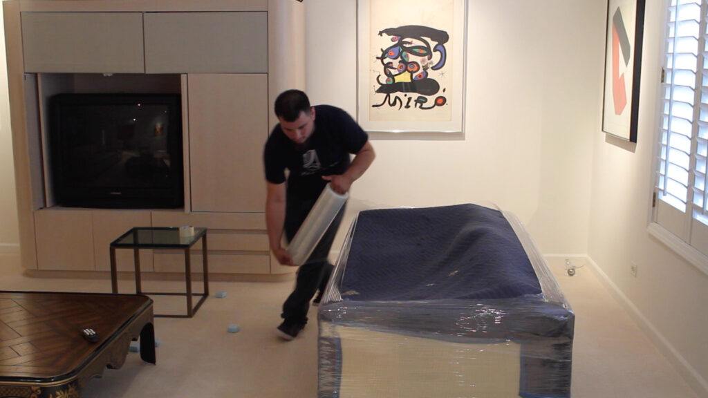 Professional movers wrap furniture to protect it during transit.